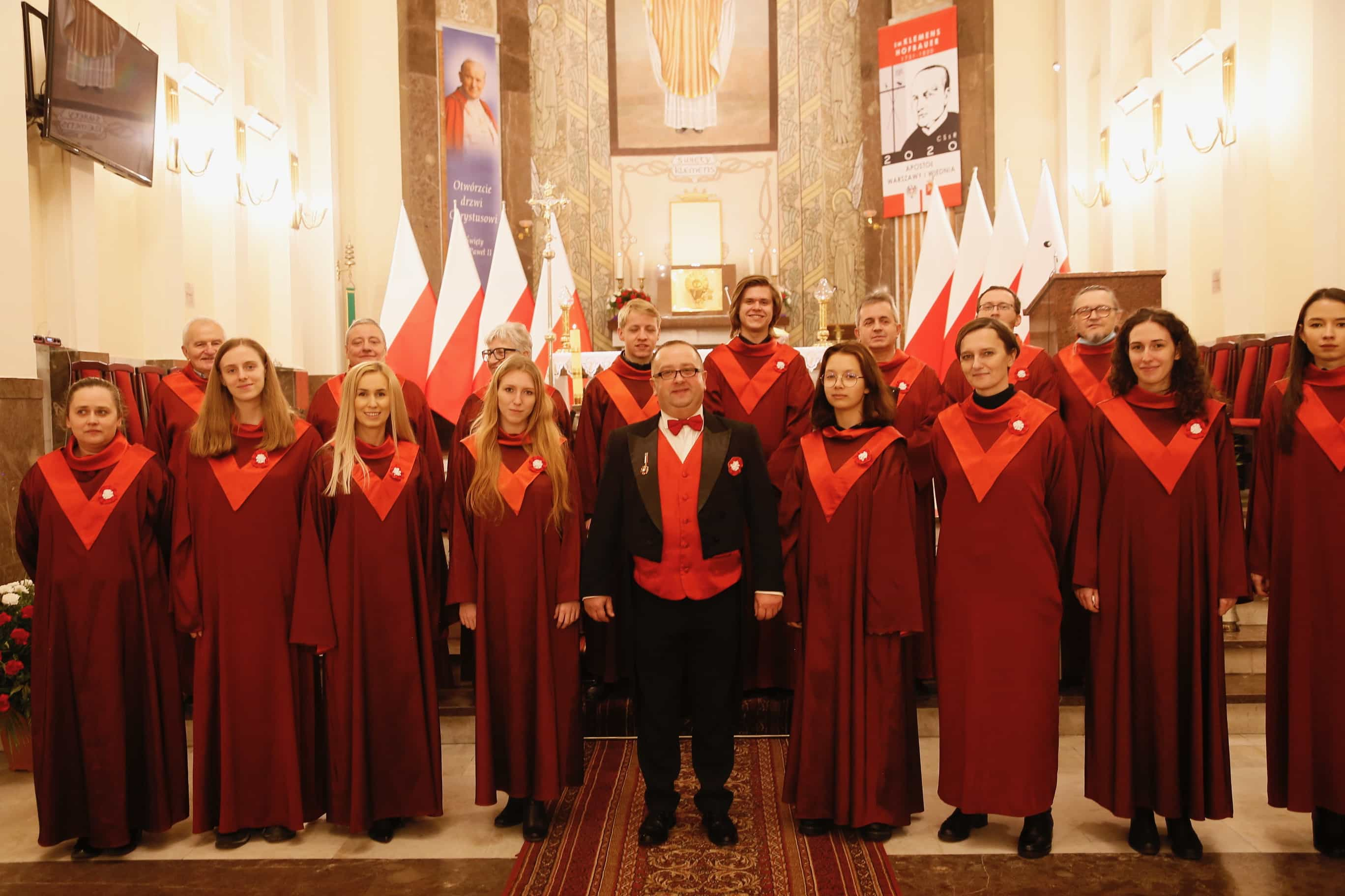 Około 17 osób niezachowujących dystansu społecznego bez maseczek. W tle obraz papieża Jana Pawła II